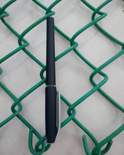 黒いペンは緑ポリ塩化ビニールに塗ったチェーン・リンクの塀に置かれ、2つの穴の長さはペンの長さと同等である。